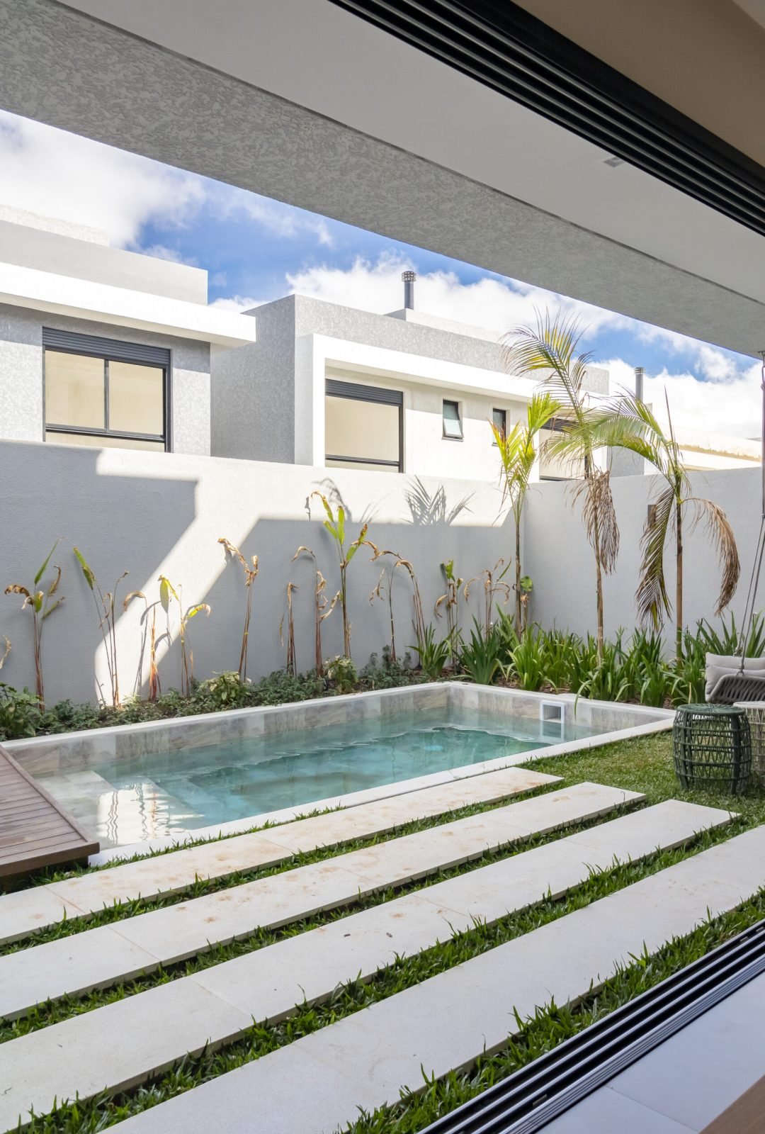 Sala de estar moderna com paredes de vidro do chão ao teto e integração com a área de lazer e piscina fotografia de arquitetura em Curitiba